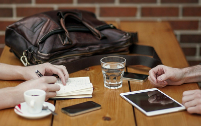 people at cafe table with tablet device and notepad