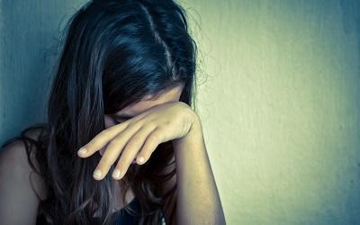 Photo of a young woman crying with her head resting on her hand