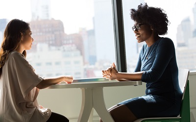 Two woman talking whilst seated at the table