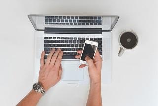 person studying a laptop with mobile phone