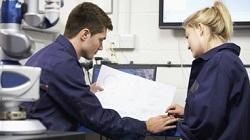 Image of a man and a woman in blue overalls looking at a paper plan 