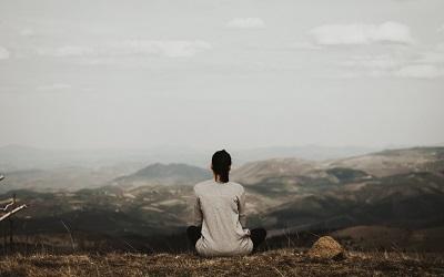 Photo by Milan Popovic on Unsplash - female sitting on a hill top alone
